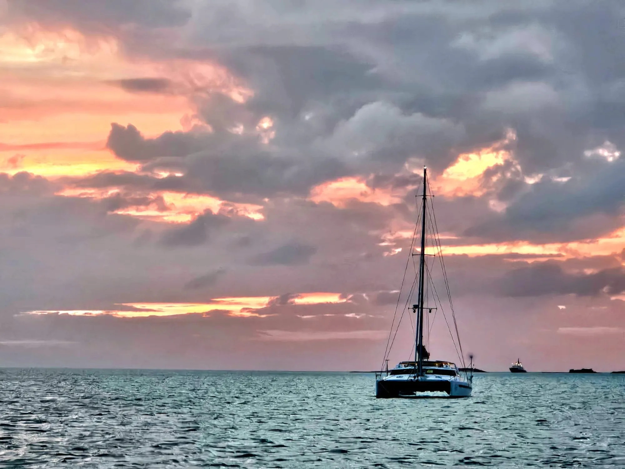 Voyage 500 catamaran silhouetted against a warm golden sunset at sea