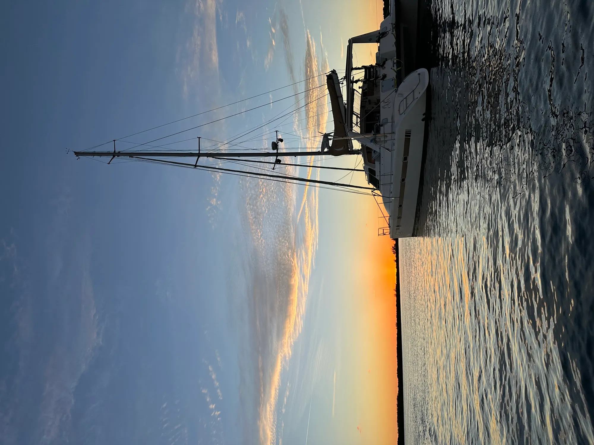 Voyage 500 catamaran sailing on a beam reach with clear skies and island coastline in the background